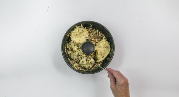 Engrasar el molde en forma de rosco (diámetro de unos 20 cm) e introducir la mitad de la masa. Espolvorear los frutos secos por encima e introducir el resto de la masa.