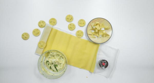 Extender la masa para pasta y, si es necesario, marcar la forma de los raviolis de unos 5 cm Ø en la mitad de la masa. Colocar pequeños trozos de relleno encima y mojar la pasta con un poco de agua con la ayuda de un cepillo.