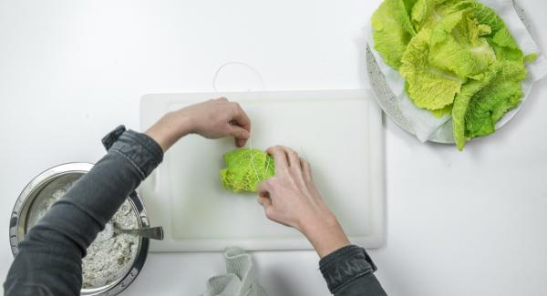 Colocar tres hojas de col de forma que se solapen ligeramente y poner el relleno de setas o de carne picada por encima, cerrar las hojas, enrollarlas y atarlas con hilo de cocina.