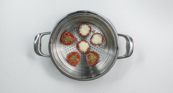 Cortar el tomate horizontalmente en rodajas y colocarlo en el accesorio súper-vapor, rociar con hierbas y extender el queso en cada rodaja con una cucharita.