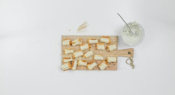 Untar cada tira de pan con un poco de crema de queso, enrollar y fijar con palillos.