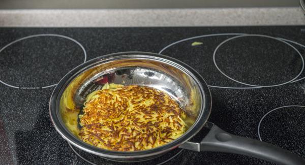 Retirar la tapa, comprobar si el rosti se despega un poco del fondo de la sartén y si se ha dorado lo suficiente. Trasladar el rosti a un plato grande para dar la vuelta. Si es necesario, volver a introducir un poco de mantequilla en la Sartén y asar el rosti por el otro lado.