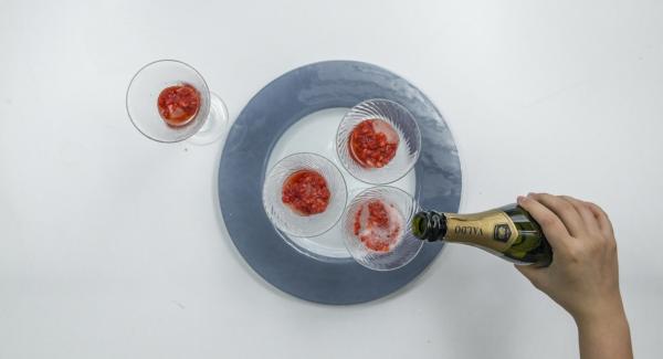 En unas copas, servir cubitos de hielo, 2-3 cucharaditas de fresas trituradas y rellenar con el prosecco/cava.