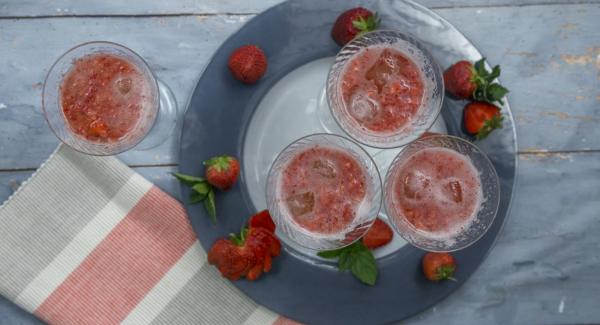 En unas copas, servir cubitos de hielo, 2-3 cucharaditas de fresas trituradas y rellenar con el prosecco/cava.