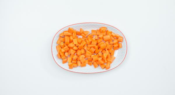 Pelar y cortar las zanahorias en dados y añadirlas a la olla junto con los guisantes y la chalota cortada en dados pequeños.
