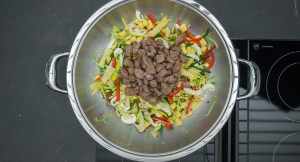 En el mismo Wok freír las verduras sin dejar de remover, añadir de nuevo la carne y sazonar con sal y pimienta.