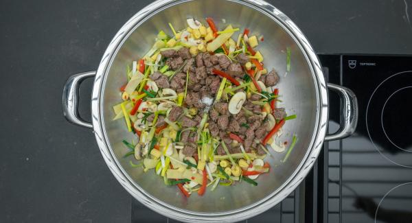 En el mismo Wok freír las verduras sin dejar de remover, añadir de nuevo la carne y sazonar con sal y pimienta.