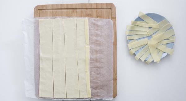 Extender la masa de hojaldre y cortar en 5 tiras. Colocar el queso en la mitad de la masa y a continuación las lonchas de jamón, dejando que sobresalgan un poco.