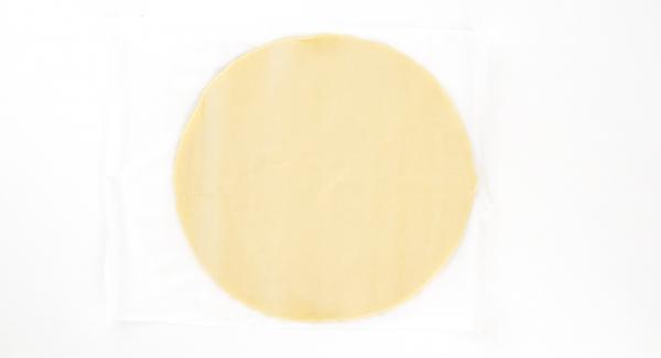 Extender el hojaldre en forma de círculo con un diámetro de unos 28 cm. Cortar un trozo de papel encerado del mismo diámetro. Colocar el hojaldre en el papel encerado.