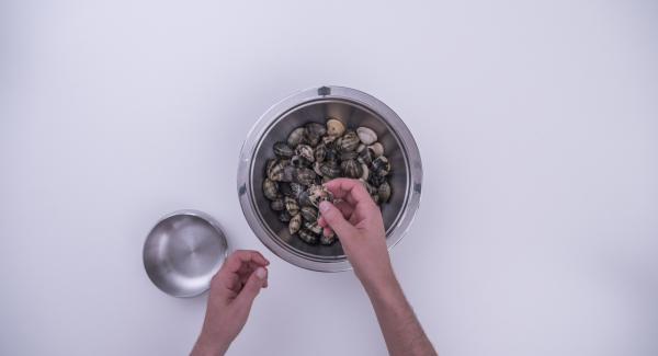 Lavar las almejas y retirar las que ya estén abiertas. Introducirlas en un bol, cubrir con agua, añadir un puñado de sal gruesa y dejar en remojo unas 2 horas. Comprobar de vez en cuando si están sacando arena. Si es así, agitarlas y cambiar el agua.