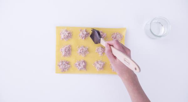 Para sellar los raviolis, untar los bordes con un poco de clara de huevo utilizando un pincel. Cubrir la hoja de pasta con el relleno con otra hoja de pasta y presionar con los dedos alrededor del relleno para que las dos hojas de pasta queden pegadas. La clara de huevo las mantendrá unidas. Con un cortador para masas, cortar los raviolis. Repetir el proceso con todas las hojas de pasta.