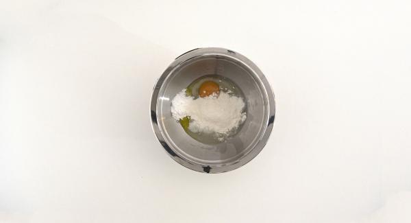 En un bol introducir el huevo, 1 cucharada de azúcar glasé, la vainilla azucarada, la levadura en polvo, el aceite de oliva virgen extra y el zumo de limón. Incorporar la harina y mezclarlo todo bien.