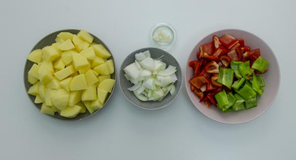 Pelar y cortar las patatas en cubos. Lavar y cortar los pimientos, también la cebolla y el ajo.