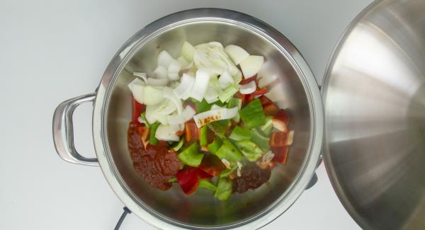 Cuando el Avisador (Audiotherm) emita un pitido al llegar a la ventana de “chuleta”, bajar temperatura de Navigenio (nivel 2) y verter el aceite, el ajo, la cebolla, los pimientos, la salsa de tomate y la pulpa de choricero. Remover y tapar.