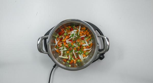 Poner las verduras, los aros de cebolleta con arroz y el caldo en una olla.