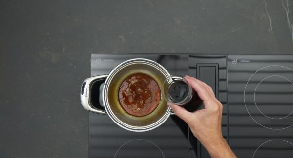 Mezclar el vino tinto y el agua y desglasar cuidadosamente el caramelo.