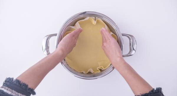 Trabajar la masa quebrada, extenderla y colocarla en el interior de la olla de 24 cm sobre un disco de papel de hornear ligeramente más grande que el fondo de la olla.