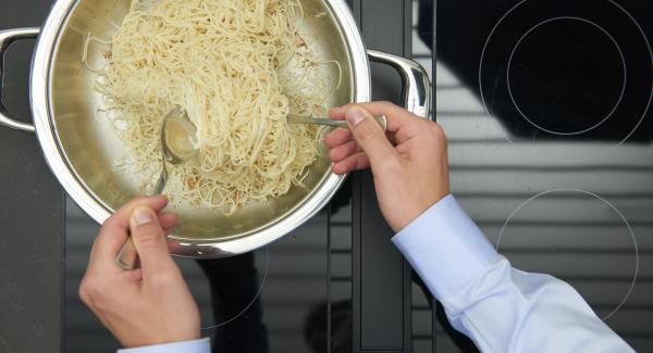 Dorar la pasta vigorosamente y retirarla. Freír brevemente las cebolletas, el pimiento,  la guindilla, el ajo y el jengibre. Añadir los langostinos y freírlos.