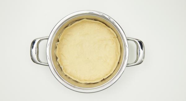 Colocar el papel de hornear en la olla, engrasar un poco el fondo de la olla. Extender la masa en Ø 26 cm y colocarla en la olla haciendo un pequeño borde. Añadir la mezcla de cebolla y la de huevos. Espolvorear con semillas de alcaravea.
