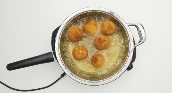 Cuando el Avisador emita un pitido al llegar a la ventana de “chuleta”, bajar temperatura de Navigenio nivel 3. Incorpora las bolas de arroz, tapar y freír. Con la ayuda del Avisador, freír hasta alcanzar los 90ºC. Dar la vuelta a las bolas y freír hasta que estén doradas, retirar y dejarlas escurrir sobre papel de cocina.