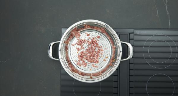 Poner los dados de bacon en el sartén y tapar. Colocar la sartén en el fuego a temperatura máxima. Encender el Avisador (Audiotherm), colocarlo en el pomo (Visiotherm) y girar hasta que se muestre el símbolo de “chuleta”.