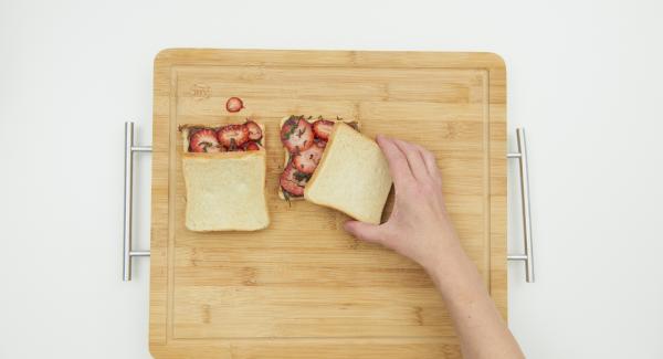 Tapar la tostada con una rebanada de pan y presionar ligeramente.