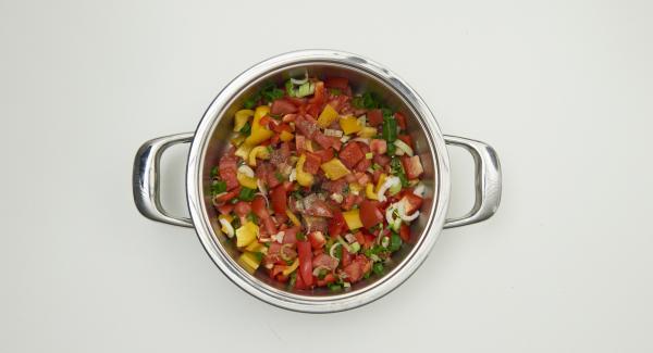 Limpiar las cebolletas, los pimientos y los tomates. Cortar todo en dados finos. Introducir las verduras troceadas en una olla.