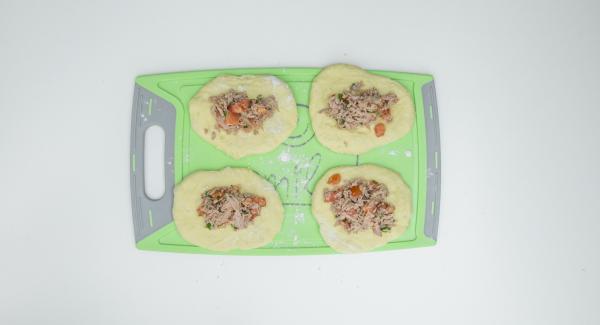 Cortar la masa en cuatro piezas, estirarla con la mano hasta que quede plana y rellenar cada una con aproximadamente dos cucharadas soperas de la mezcla de atún. Cerrar la masa sobre el relleno y enrollar hasta formar bolas. Cortar la masa en cuatro piezas, estirarla con la mano hasta que quede plana y rellenar cada una con aproximadamente dos cucharadas soperas de la mezcla de atún. Cerrar la masa sobre el relleno y enrollar hasta formar bolas.