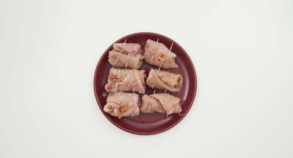 Distribuir la mezcla de carne picada sobre la carne, enrollar y fijar con un palillo.