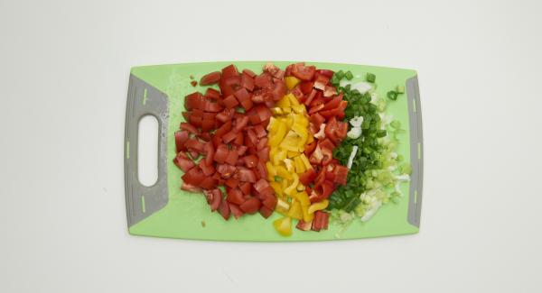 Limpiar las cebolletas, los pimientos y los tomates. Cortar todo en dados finos. Introducir las verduras troceadas en una olla.
