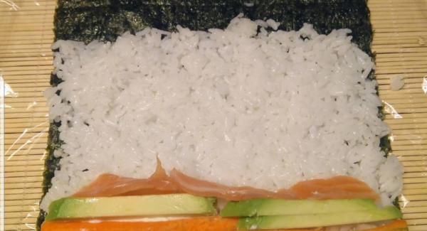 Humedecemos las manos y vamos extendiendo una capa fina de arroz por el alga, dejando al final un trozo de un par de centímetros sin arroz y rellenando al gusto